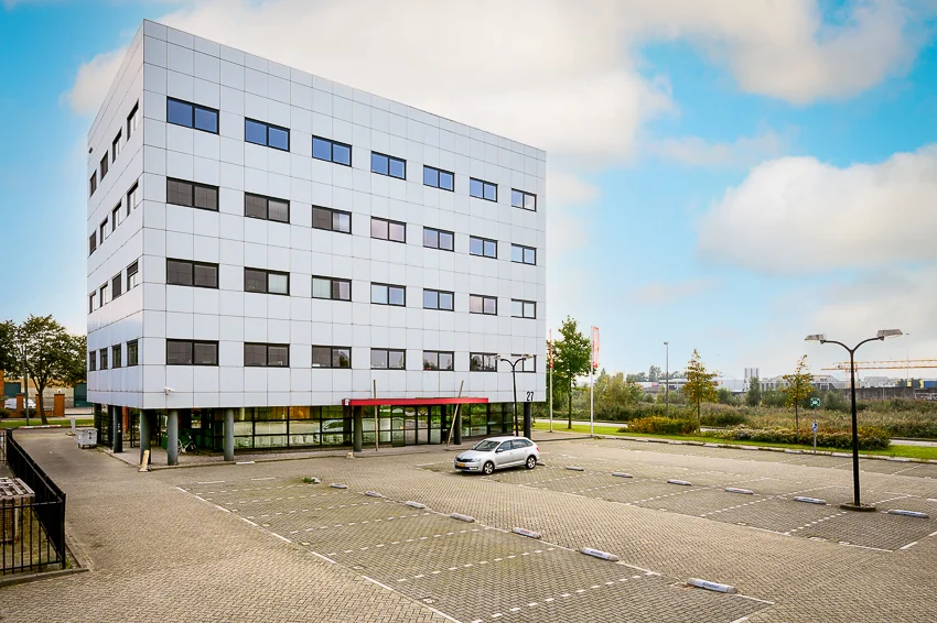 Modern kantoorgebouw aan de Karel Doormanweg met een deels lege parkeerplaats op de voorgrond.